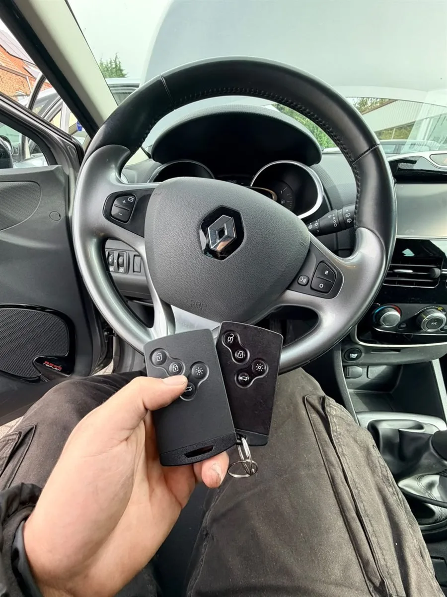 Deux cartes clés Renault tenues devant le volant d'une voiture