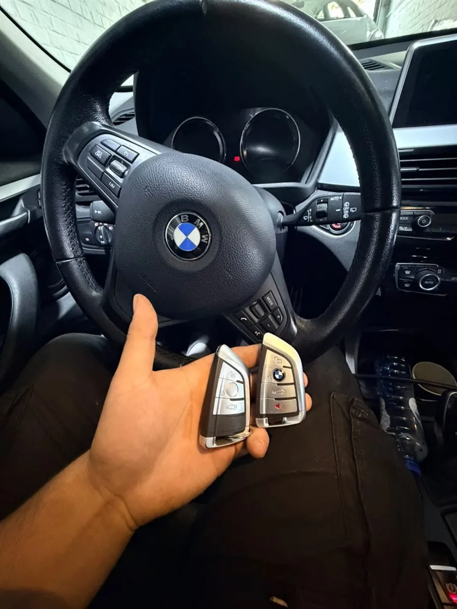 Deux clés BMW tenues devant le volant d'une voiture