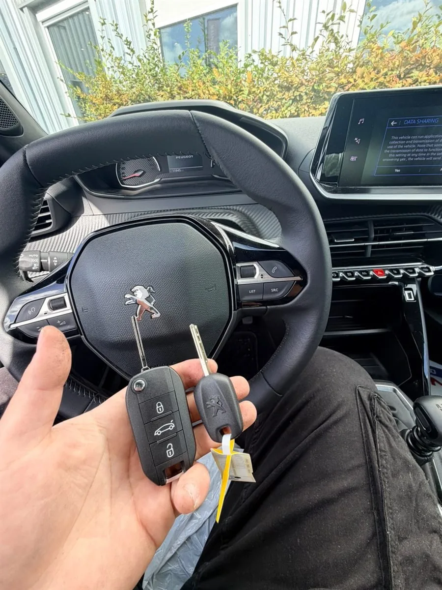 Clé Peugeot tenue devant le volant d'une voiture ouverte