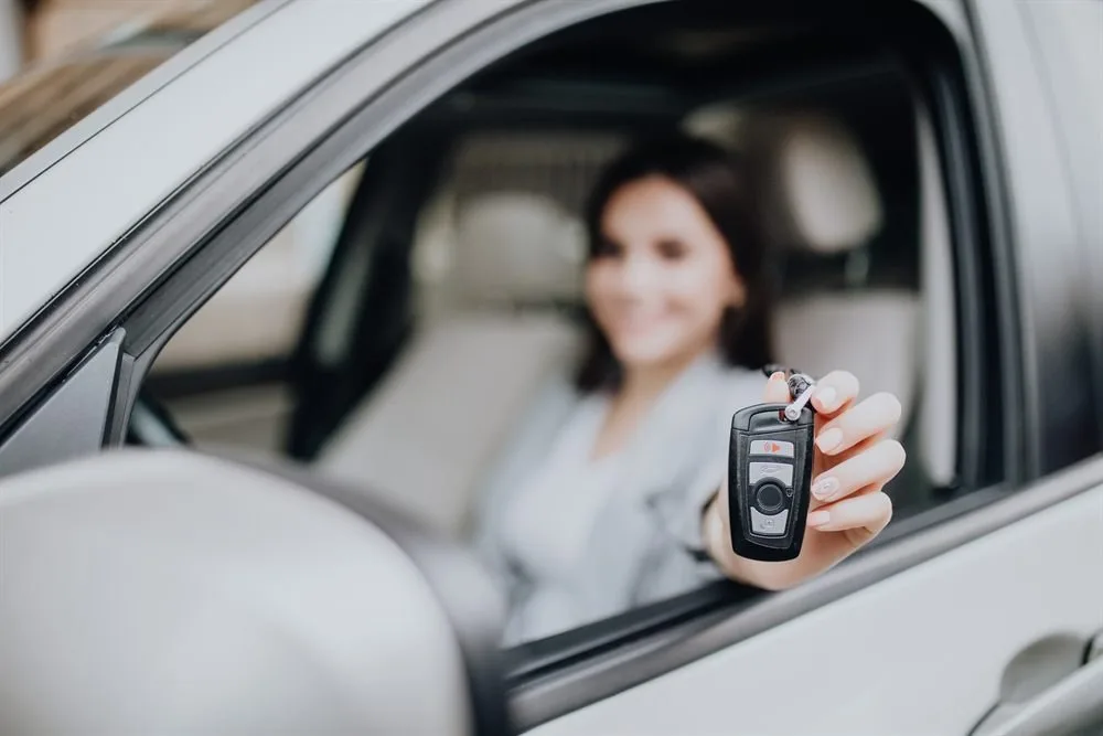 Conductrice tenant une clé de voiture à la fenêtre de son véhicule