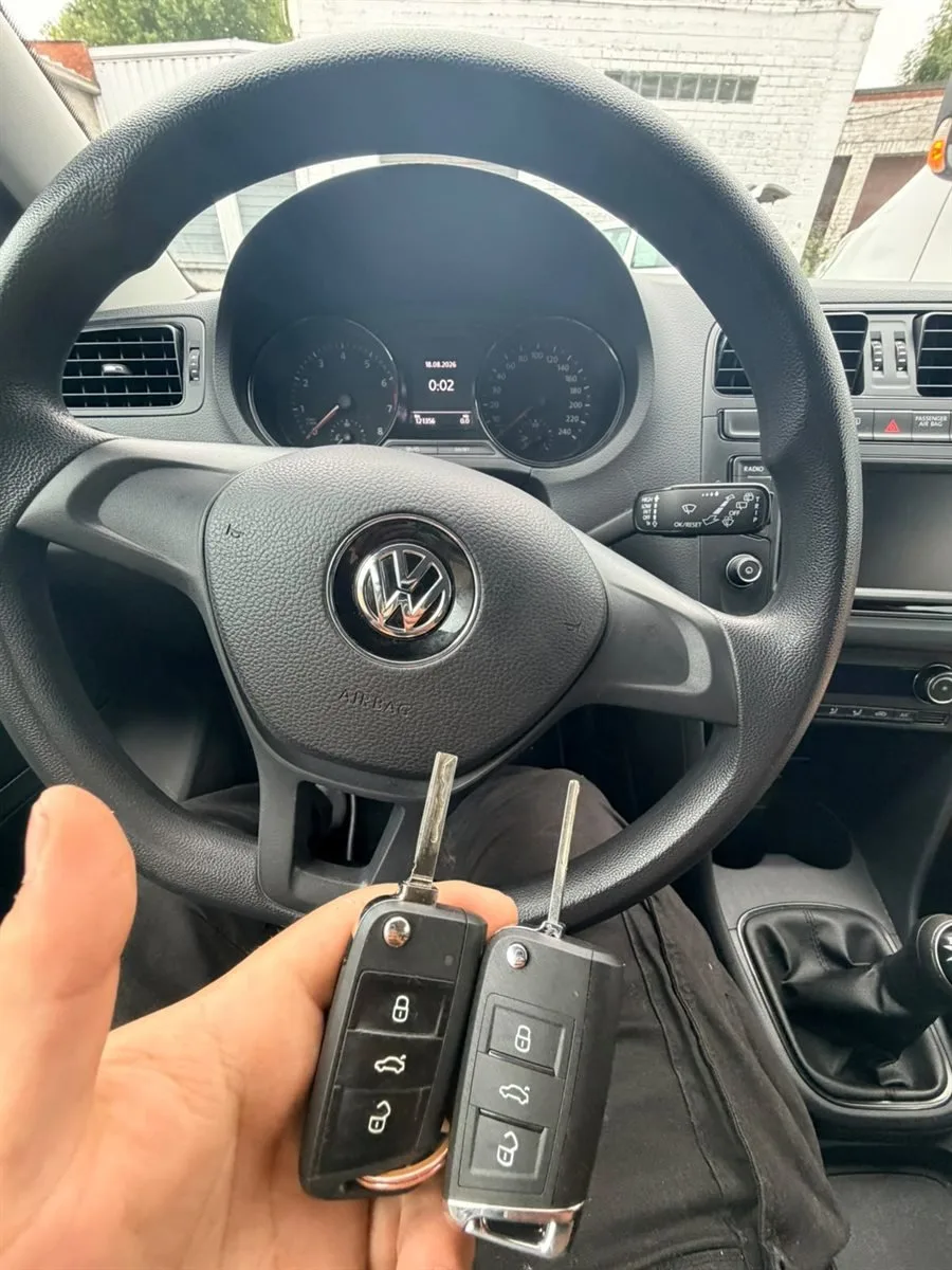 Deux clés pliantes Volkswagen tenues devant le volant