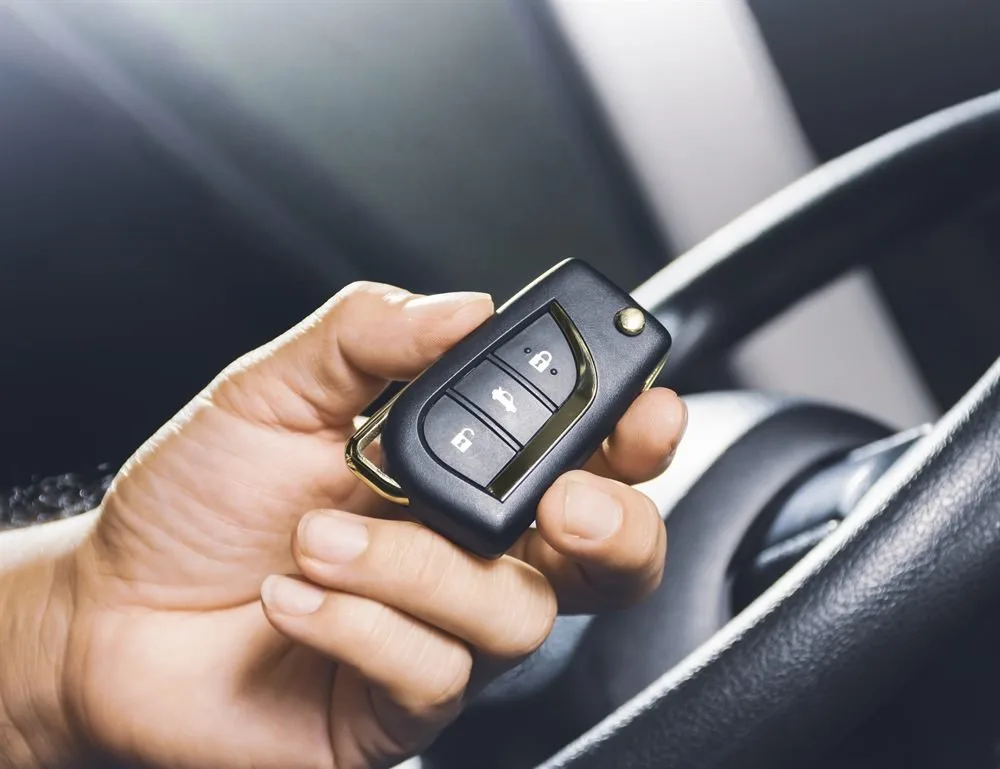 Main tenant une clé de voiture à télécommande devant le volant